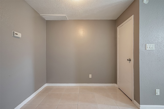 unfurnished room featuring a textured ceiling and light tile patterned flooring