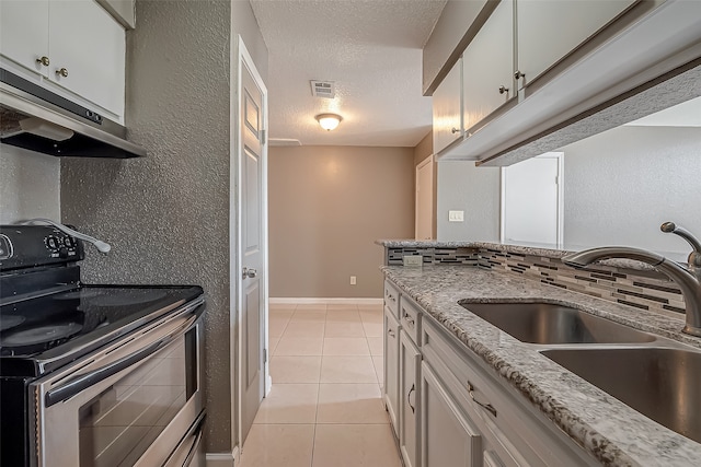 kitchen featuring electric stove, light stone counters, white cabinetry, and sink