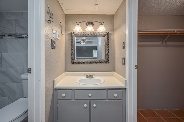 bathroom with tile patterned flooring, a textured ceiling, vanity, and toilet