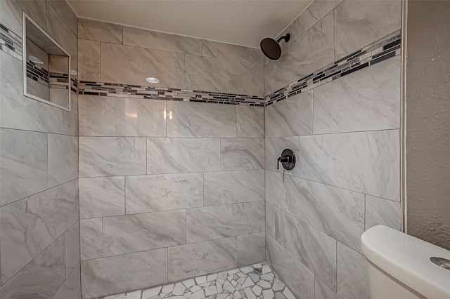 bathroom featuring tiled shower and toilet