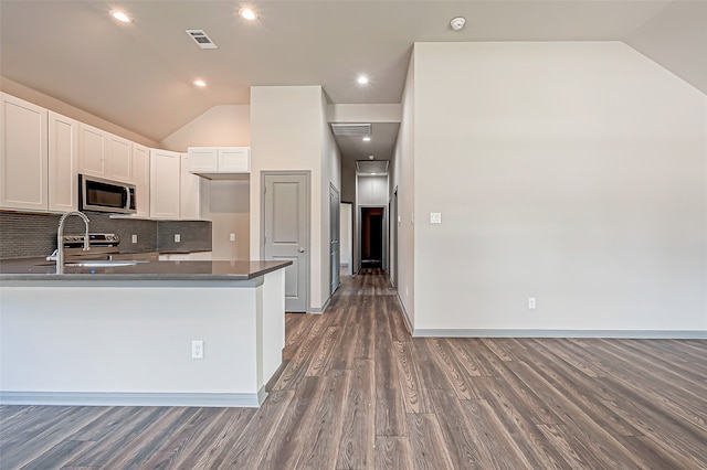 kitchen featuring dark hardwood / wood-style floors, white cabinetry, kitchen peninsula, vaulted ceiling, and appliances with stainless steel finishes