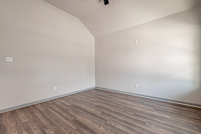 spare room with dark hardwood / wood-style floors and vaulted ceiling