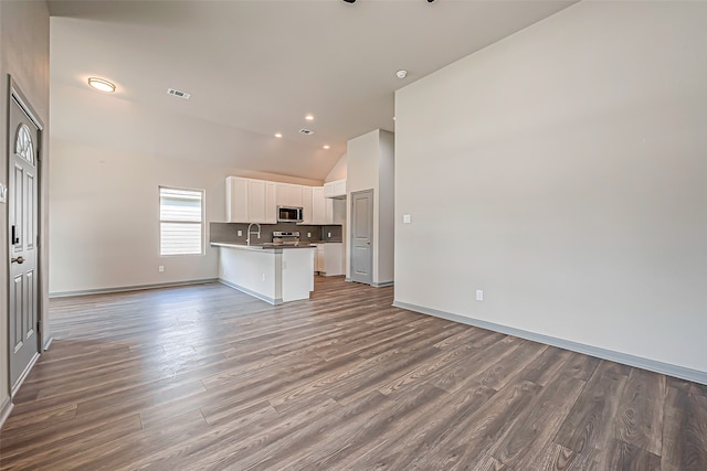 unfurnished living room featuring dark hardwood / wood-style floors, sink, and high vaulted ceiling