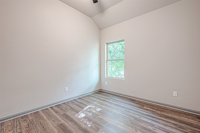 unfurnished room featuring lofted ceiling and hardwood / wood-style floors