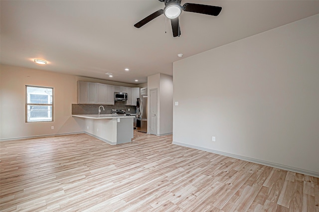 kitchen with a breakfast bar area, white cabinets, kitchen peninsula, light hardwood / wood-style flooring, and appliances with stainless steel finishes