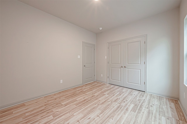 unfurnished bedroom with light hardwood / wood-style flooring and a closet