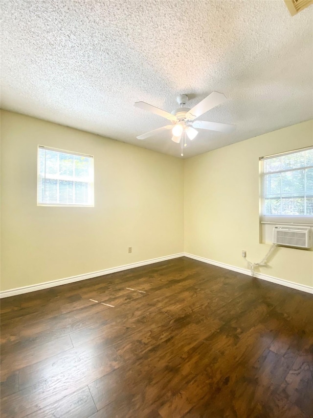 empty room featuring ceiling fan, dark hardwood / wood-style floors, cooling unit, and a textured ceiling