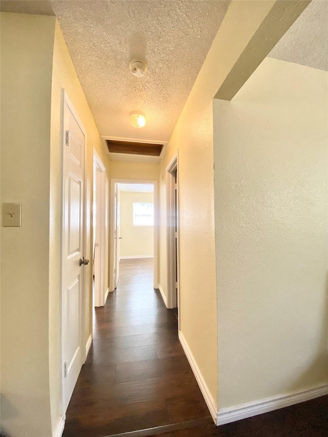 hallway with dark hardwood / wood-style floors and a textured ceiling