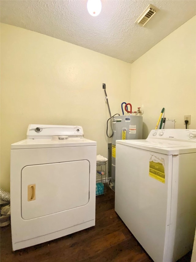 laundry area with dark wood-type flooring, electric water heater, washing machine and dryer, and a textured ceiling