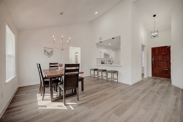 dining space featuring a high ceiling, light hardwood / wood-style flooring, and a chandelier