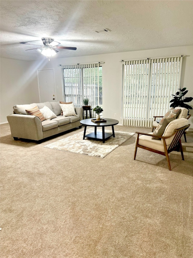 carpeted living room featuring a textured ceiling and ceiling fan