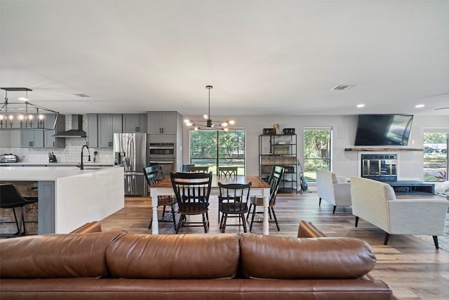 living room with light wood-type flooring, an inviting chandelier, a healthy amount of sunlight, and sink