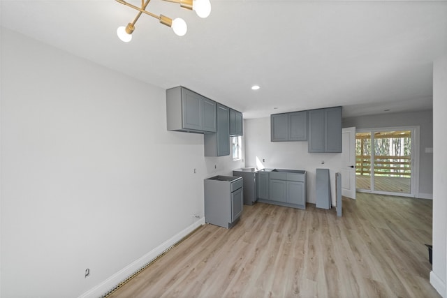 kitchen with gray cabinetry, light hardwood / wood-style flooring, and a notable chandelier