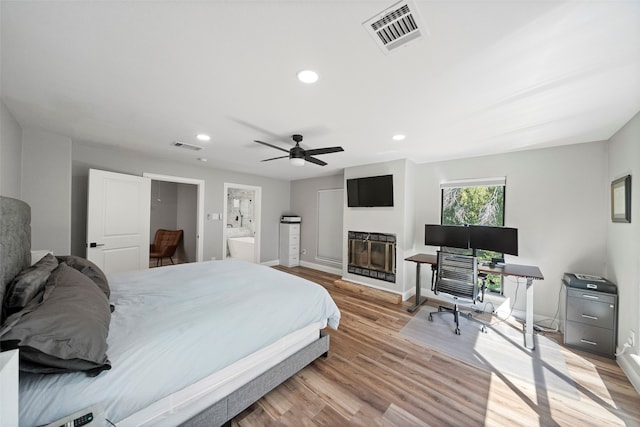 bedroom featuring light hardwood / wood-style floors, ceiling fan, and ensuite bathroom