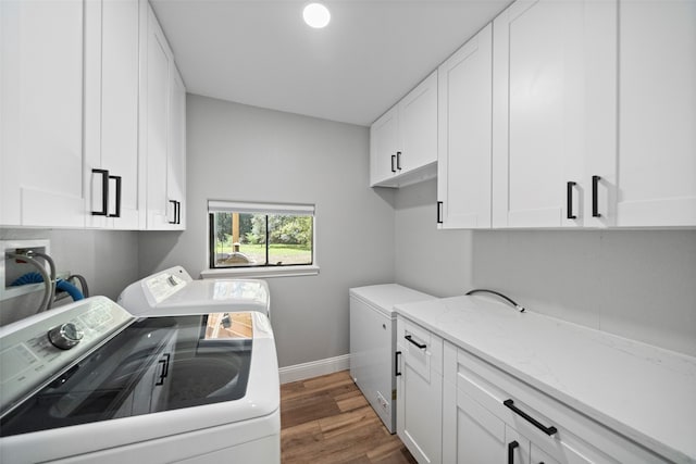 laundry room featuring dark hardwood / wood-style flooring, washer and clothes dryer, and cabinets