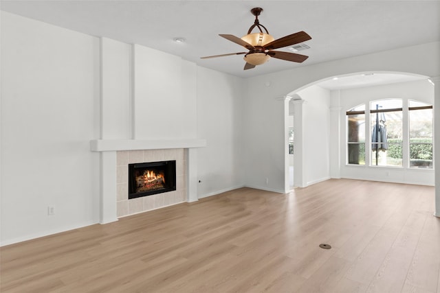 unfurnished living room with light wood-type flooring, visible vents, a fireplace, and ceiling fan