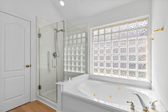 bathroom featuring a jetted tub, vaulted ceiling, a shower stall, and wood finished floors