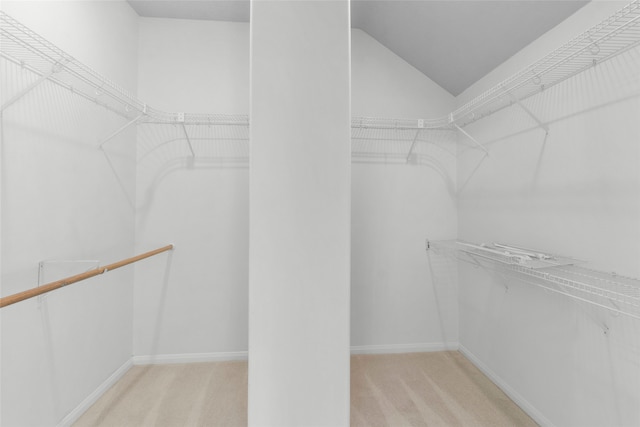 spacious closet with lofted ceiling and light carpet