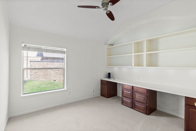 unfurnished office featuring lofted ceiling, light colored carpet, a ceiling fan, and built in study area