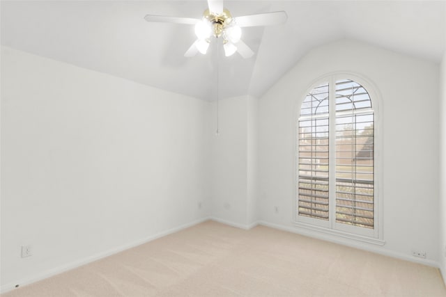 spare room with a ceiling fan, light colored carpet, vaulted ceiling, and baseboards