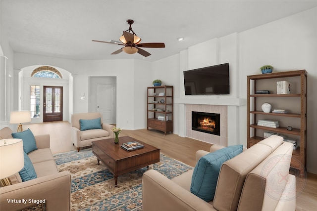 living room with ceiling fan, a fireplace, and light wood-style flooring