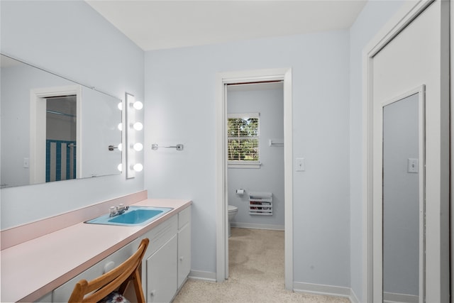 bathroom with vanity, heating unit, and toilet