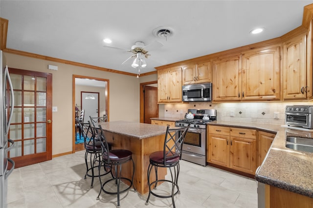 kitchen featuring a breakfast bar, light tile patterned flooring, appliances with stainless steel finishes, tasteful backsplash, and a kitchen island