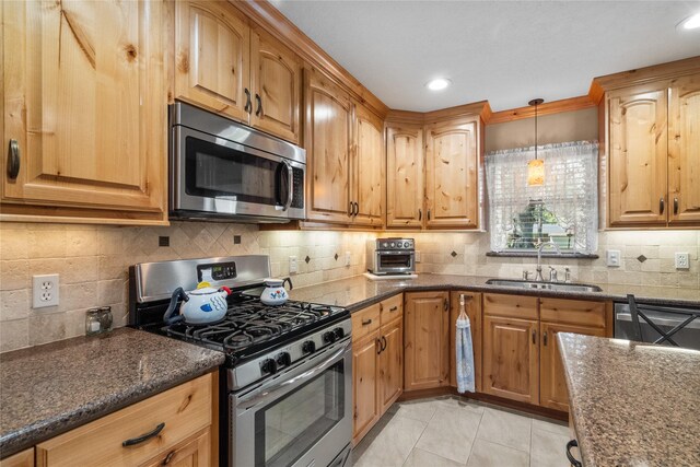 kitchen featuring tasteful backsplash, sink, light tile patterned floors, and appliances with stainless steel finishes