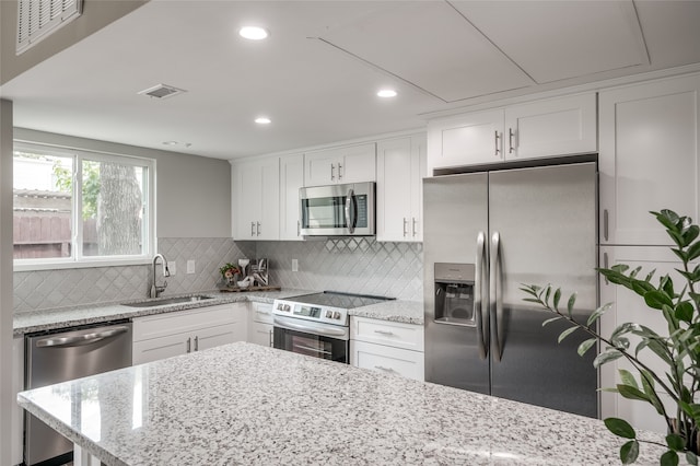 kitchen featuring light stone counters, appliances with stainless steel finishes, sink, and white cabinetry