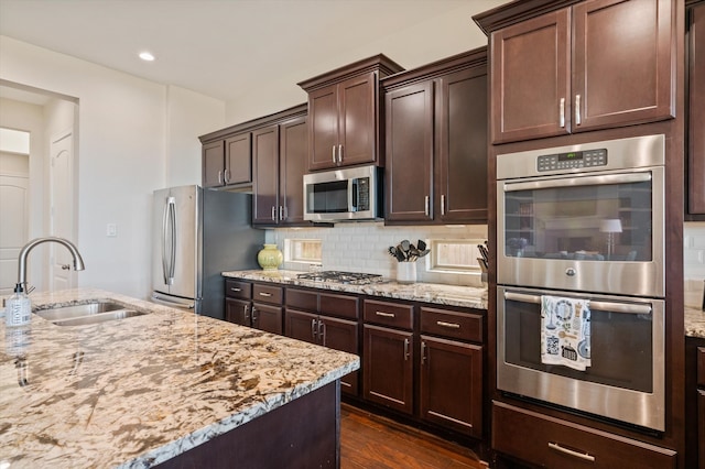 kitchen with dark brown cabinetry, sink, tasteful backsplash, stainless steel appliances, and dark hardwood / wood-style flooring