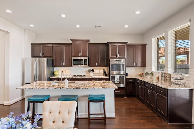 kitchen with sink, stainless steel appliances, a center island, a kitchen bar, and dark hardwood / wood-style flooring