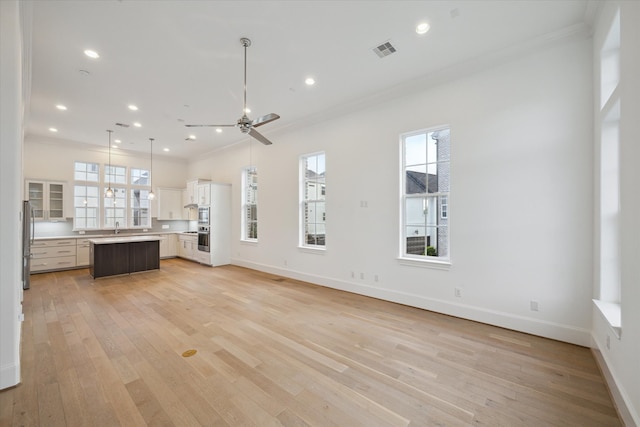 unfurnished living room with ceiling fan, light hardwood / wood-style flooring, crown molding, and sink