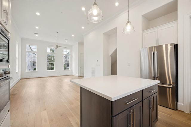 kitchen with ceiling fan, white cabinets, dark brown cabinetry, appliances with stainless steel finishes, and light wood-type flooring