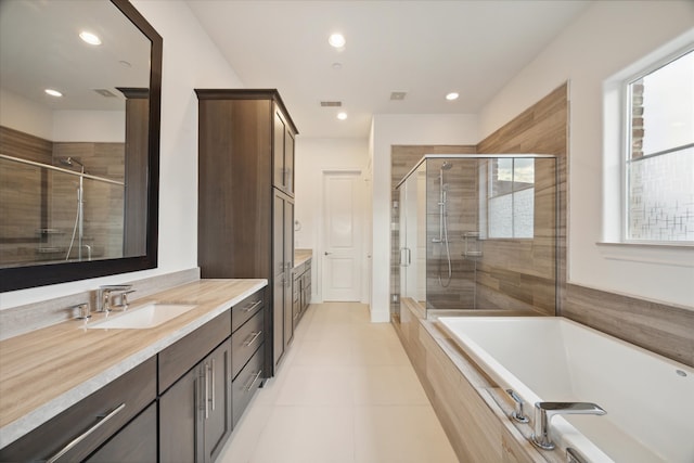 bathroom with tile patterned flooring, independent shower and bath, and vanity