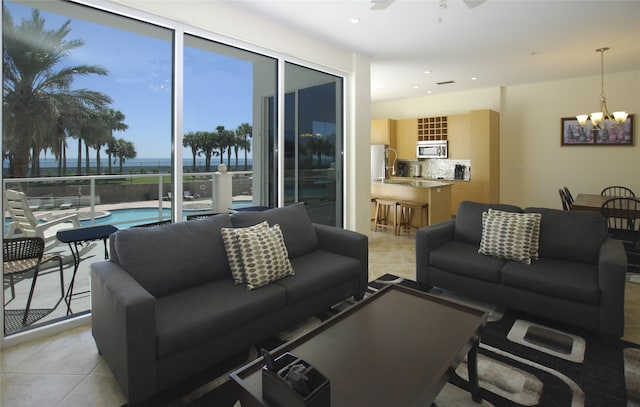 living room featuring ceiling fan with notable chandelier, a water view, and light tile patterned floors