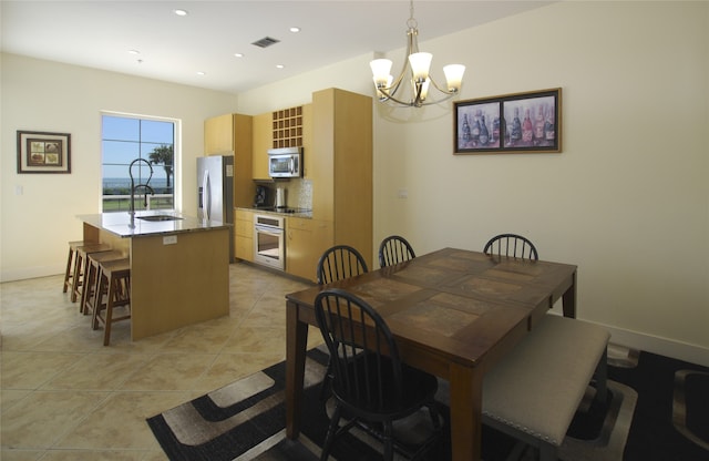 dining area featuring a notable chandelier, sink, and light tile patterned flooring