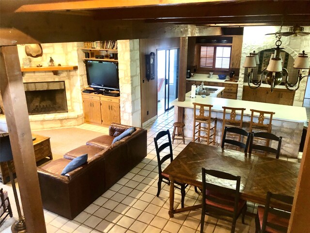 living room featuring a stone fireplace, sink, and light tile patterned floors