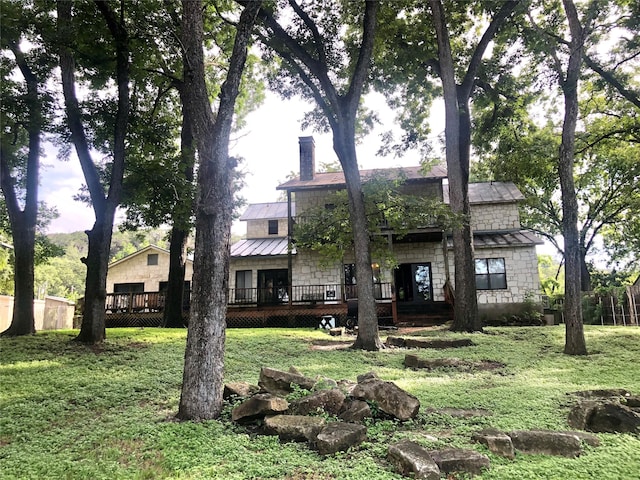 back of property featuring a wooden deck and a lawn