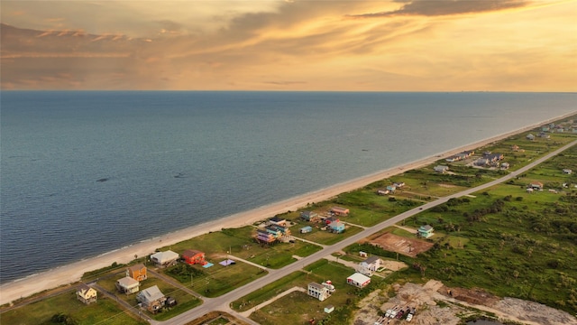 aerial view at dusk with a view of the beach and a water view