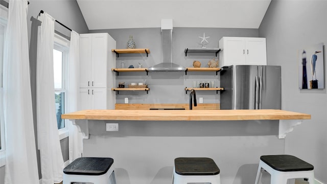 kitchen featuring white cabinets, island exhaust hood, vaulted ceiling, and a breakfast bar