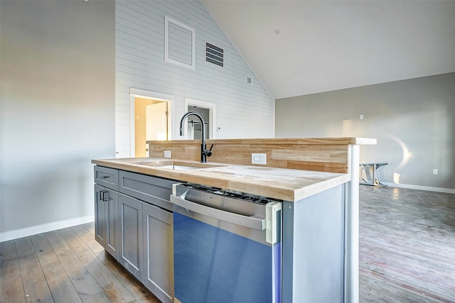 kitchen with high vaulted ceiling, dishwasher, wooden counters, hardwood / wood-style floors, and sink