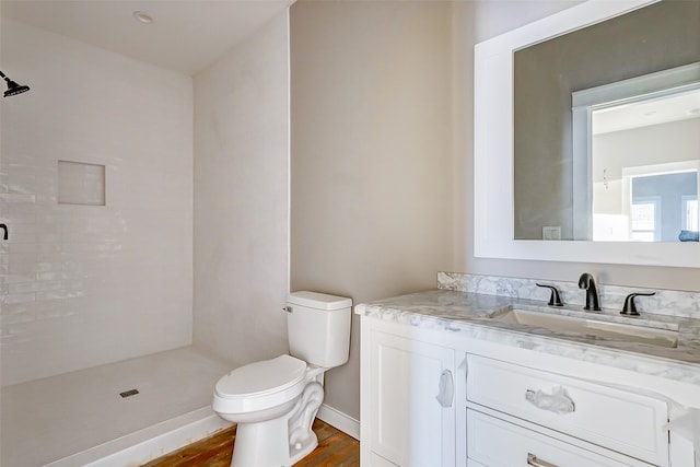 bathroom with hardwood / wood-style flooring, walk in shower, vanity, and toilet