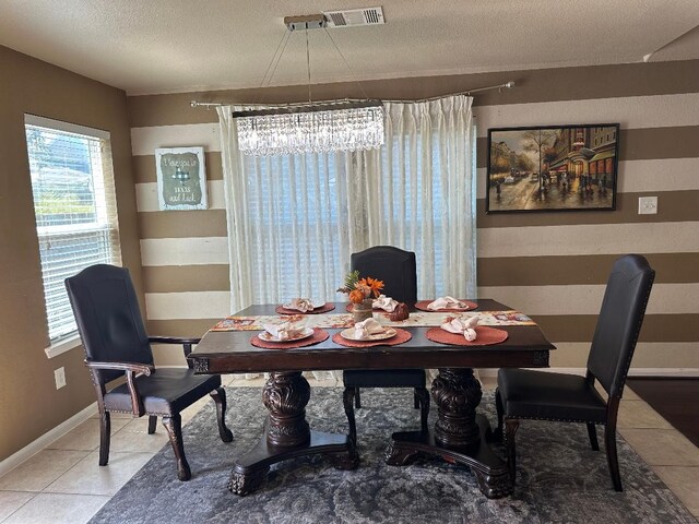 dining space featuring a textured ceiling, tile patterned flooring, and an inviting chandelier