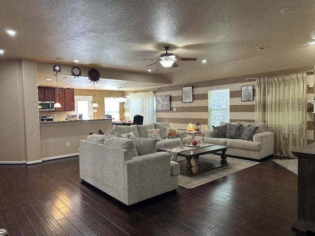 living room featuring ceiling fan, a textured ceiling, dark hardwood / wood-style floors, and a healthy amount of sunlight