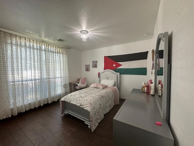 bedroom with a textured ceiling and dark hardwood / wood-style flooring