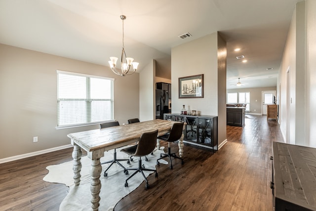 dining room with ceiling fan with notable chandelier and dark hardwood / wood-style flooring