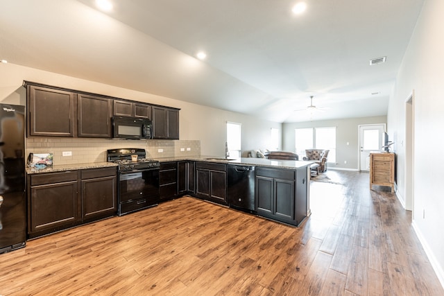 kitchen featuring lofted ceiling, kitchen peninsula, light hardwood / wood-style flooring, black appliances, and ceiling fan