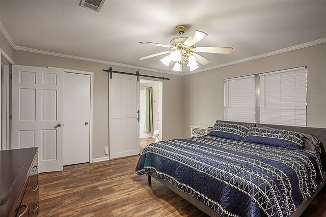 bedroom featuring a barn door, crown molding, dark hardwood / wood-style floors, and ceiling fan