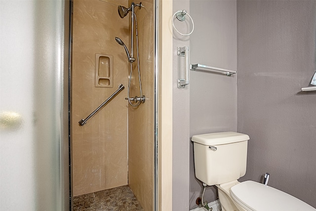 bathroom featuring a shower with door and toilet