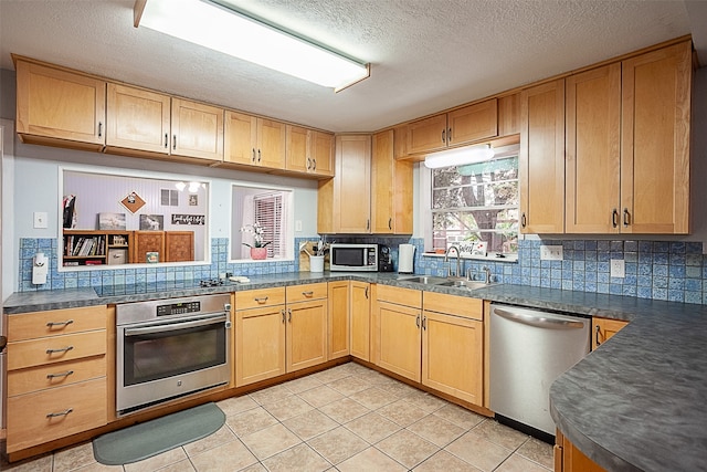 kitchen featuring a textured ceiling, tasteful backsplash, sink, stainless steel appliances, and light tile patterned floors